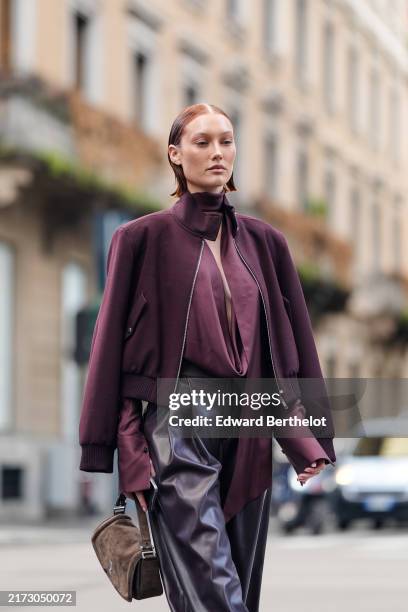 Meredith Duxbury wears dark red maroon v-neck long sleeve Boss shirt, dark red maroon cropped unzipped Boss jacket, shiny black loose high waisted...