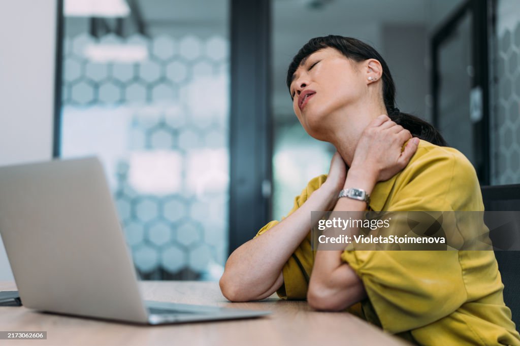Businesswoman suffering from neckache while working in the office.