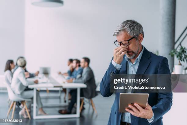businessman with headache during a meeting in the office. - sobrecarregado imagens e fotografias de stock