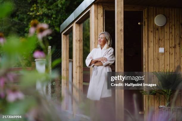 beautiful older woman relaxing after spa session in home sauna. concept of hygge and slow life for senior people. - spa sauna stock pictures, royalty-free photos & images