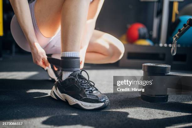person securing ankle weight in modern gym setting - ankle weights stock pictures, royalty-free photos & images