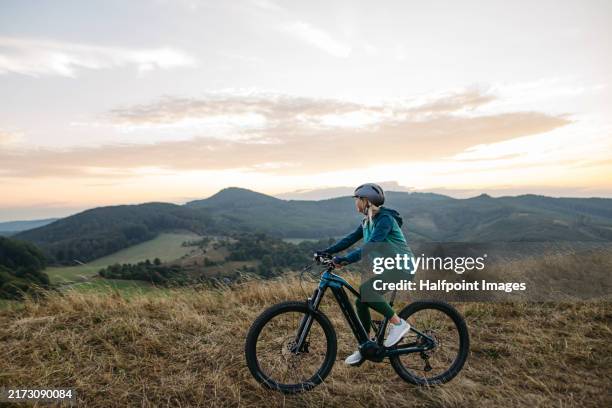 senior woman on bike ride in autumn nature, enjoying beautiful landscape. active older woman on electric bicycle. - elcykel bildbanksfoton och bilder