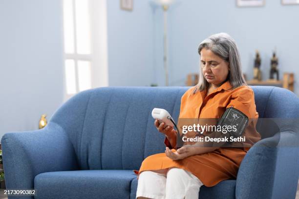 senior woman measuring her blood pressure stock photo - blood pressure gauge stock pictures, royalty-free photos & images