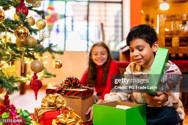 child siblings open gifts on christmas at home - parcel stock pictures, royalty-free photos & images