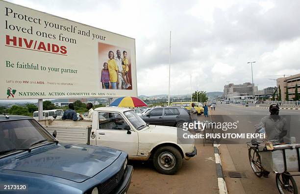 Dairy street vendor walks next a bilboard campaign against HIV AIDS 10 July 2003, in Abuja. US President George W. Bush will arrive 11 July to...