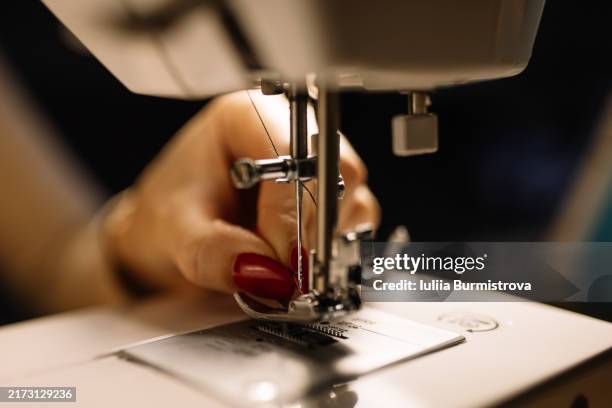 delicate female hand delicately thread slender string through eye of sewing machine needle - macchina per cucire foto e immagini stock