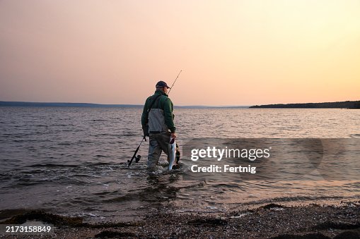 A Striped Bass fisherman on a beach in Nova Scotia with a nice fish A Striped Bass fisherman on a beach in Nova Scotia with a nice fish