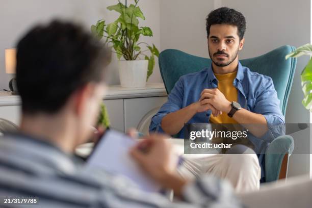 the psychologist listens to his patient with problems at home and takes notes in his notebook - std test stock pictures, royalty-free photos & images