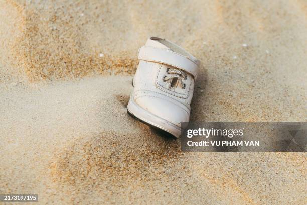 single kid shoe forgotten on the beach - white shoe stock pictures, royalty-free photos & images