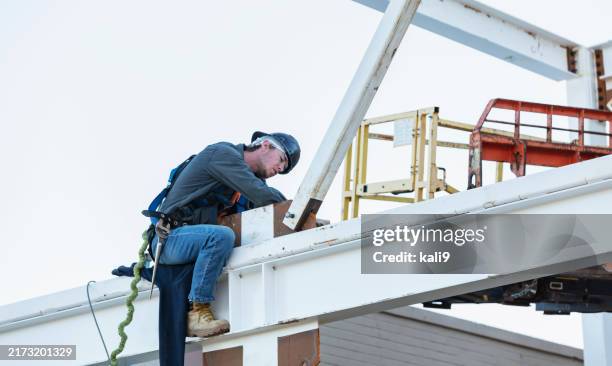 ironworker on steel beam with safety harness, bolting - builders boots stock pictures, royalty-free photos & images