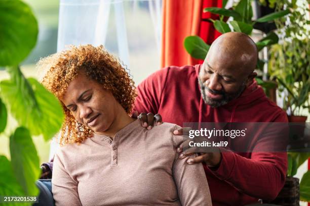 mature man massaging wife's shoulder, at home - mature couple massage photos et images de collection