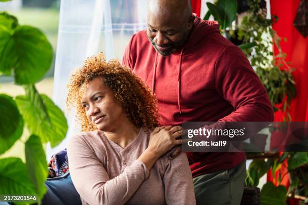 mature man massaging wife's shoulder, at home - mature couple massage photos et images de collection