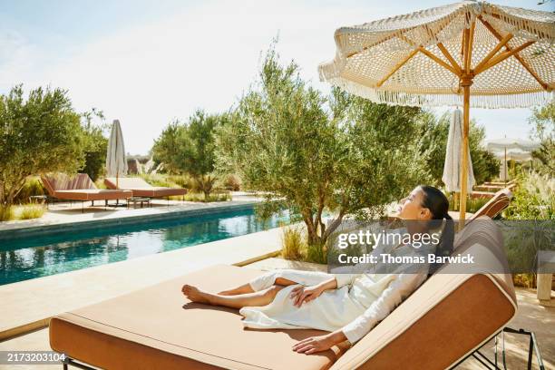 wide shot woman relaxing by pool at luxury tropical boutique resort - hotel de luxo imagens e fotografias de stock