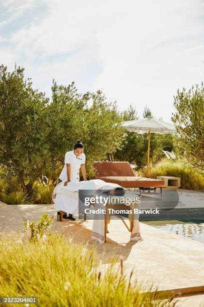 wide shot guest receiving poolside massage at tropical luxury resort - banc de massage photos et images de collection