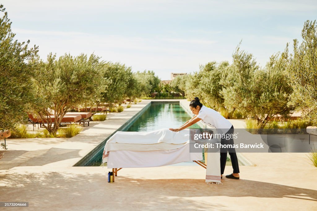 Wide shot guest receiving poolside massage at tropical luxury resort