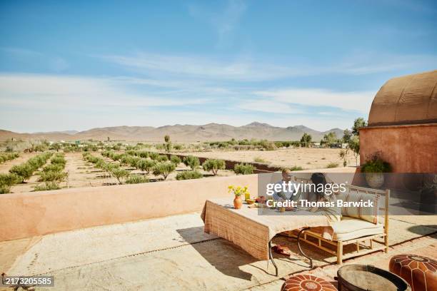 extreme wide shot couple relaxing on rooftop terrace of luxury resort - exotic food stock pictures, royalty-free photos & images