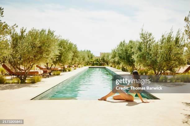 wide shot woman sitting poolside at luxury boutique resort - wide shot stock pictures, royalty-free photos & images