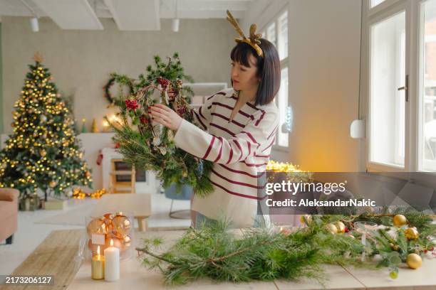 young woman making a christmas wreath - coniferous tree stock pictures, royalty-free photos & images