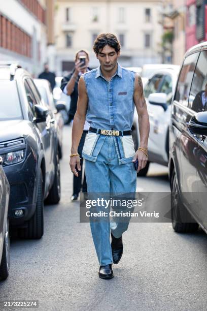 Guest wears denim vest, jeans, black belt outside Moschino during the Milan Fashion Week Menswear Spring/Summer 2025 on September 19, 2024 in Milan,...