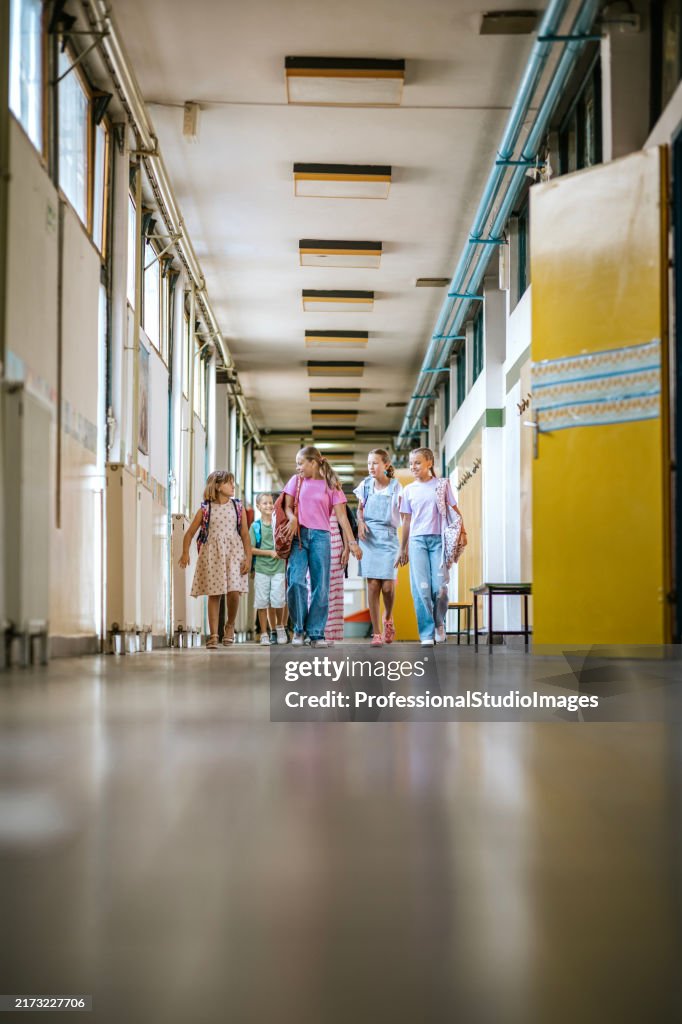 Students walk through the school corridor, chatting and laughing in a lively atmosphere during school hours