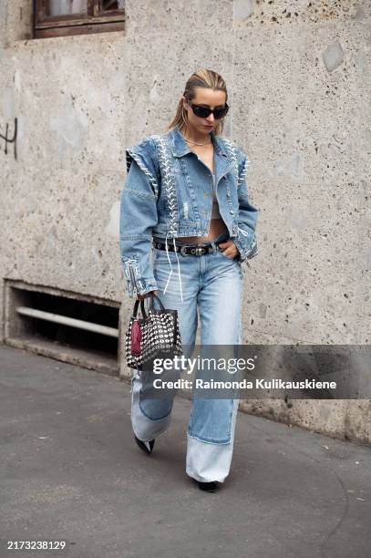 Julia Comil wears blue jeans, black leather belt, blue denim jacket with white details, sunglasses and black platform shoes outside Tokyo James show...