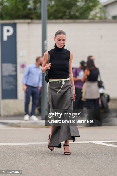 Sophia Roe wears black turtleneck sleeveless Prada shirt, silver rings, dark gray light green drawstring mermaid Prada midi skirt, black open toe...