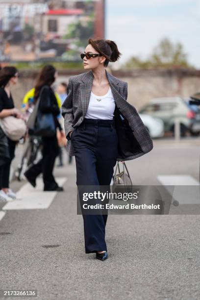 Doudou Babe wears black Prada sunglasses, white Prada tank top, dark gray pattern oversized blazer jacket, black high waisted pants, shiny black...