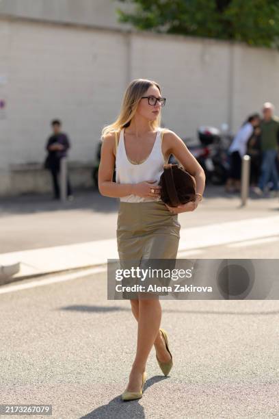 Guest wearing a white silk camisole tucked into a beige pencil skirt, a brown clutch is seen outside the Prada show during the Milan Fashion Week...