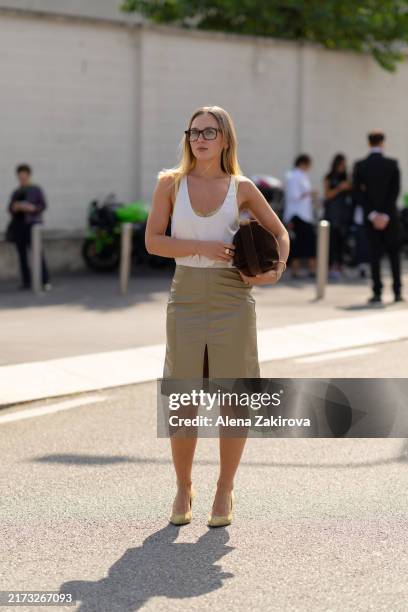 Guest wearing a white silk camisole tucked into a beige pencil skirt, a brown clutch is seen outside the Prada show during the Milan Fashion Week...