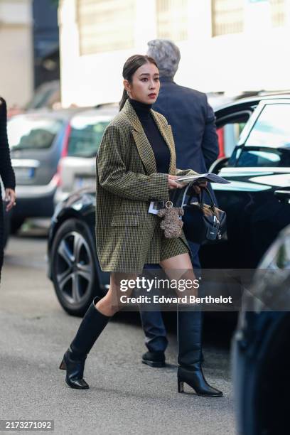 Guest wears a black turtleneck pullover, a green oversized blazer jacket, a black leather bag, black leather boots, outside Max Mara, during the...