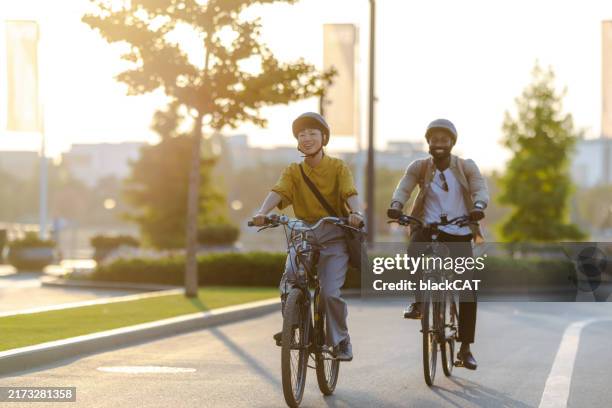 two cyclists riding along a scenic path on a sunny day. daily commuting to work - bicycle lane stock pictures, royalty-free photos & images