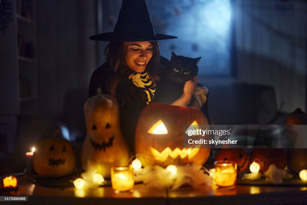 Happy witch with black cat on Halloween night.