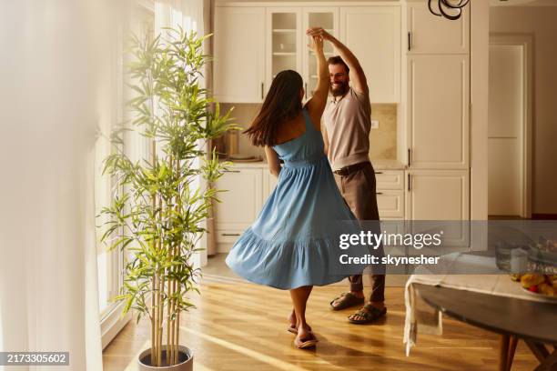 pareja despreocupada divirtiéndose mientras baila en casa. - bailar fotografías e imágenes de stock