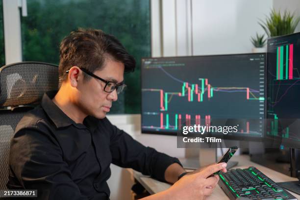 stock trader monitoring financial charts and phone data - bureau de change photos et images de collection