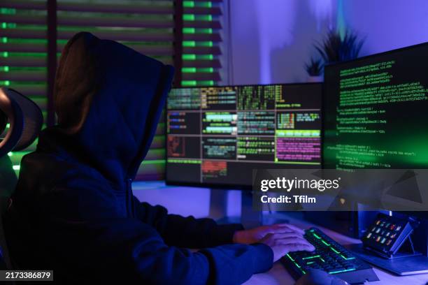 hacker coding in dark room with multiple screens - spyware stock pictures, royalty-free photos & images