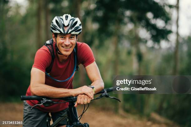 portrait of a beautiful man sitting on his bike and looking at camera - ciclista foto e immagini stock