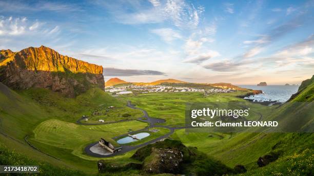 panorama of heimaey at sunset, with a view on cliffs, pastures, the helgafell and eldfell volcanoes, the main village and other desert islands of the archipelago of the westman islands (vestmannaeyjar) - south iceland (suðurland). - aktiver vulkan stock-fotos und bilder