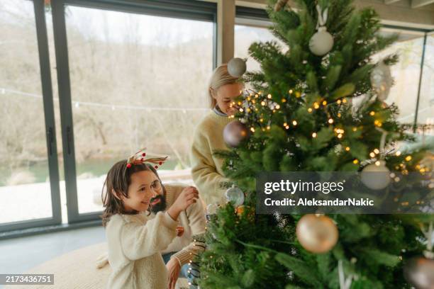 decorating christmas tree together - decorar fotografías e imágenes de stock