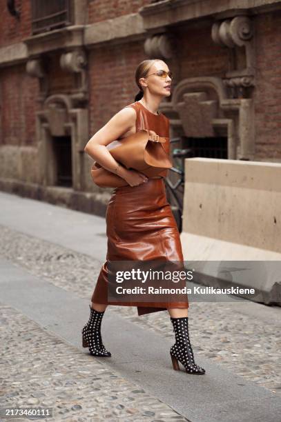 Viky Rader wears brown leather skirt, matching top, brown bag and black shoes with metal details outside Sportmax show during the Milan Fashion Week...