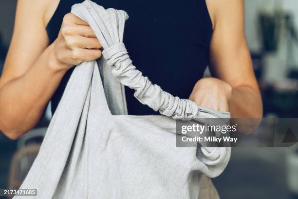 close-up of a woman’s hands organizing a linen bag strap, emphasizing simplicity and sustainable fashion. concept of minimalism and eco-friendly lifestyle. - todesopfer stock-fotos und bilder