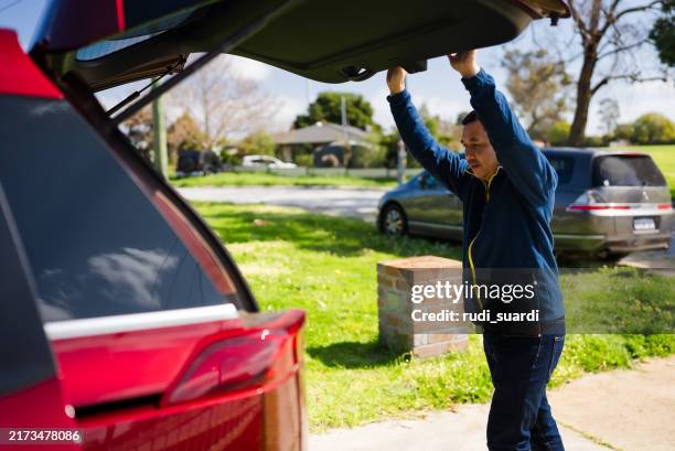 mature adult closing car trunk door - achterbak-van-auto stockfoto's en -beelden