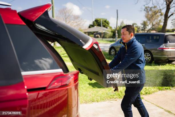 mature adult closing car trunk door - achterbak-van-auto stockfoto's en -beelden