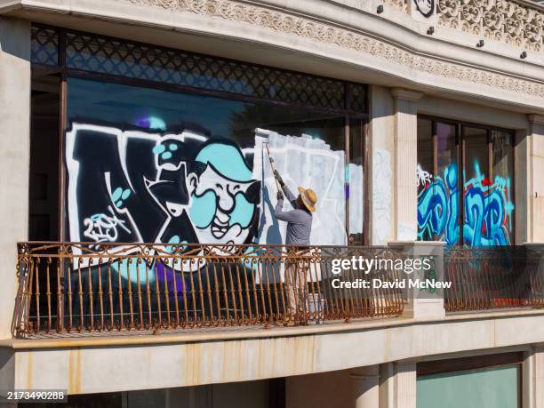 In an aerial view, workers paint the second of two mansions covered with graffiti, this one vandalized within the past few days according to...