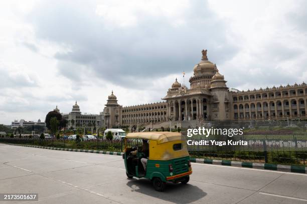 auto rickshaw (tuk tuk) passing vidhana soudha: blend of traditional and modern bangalore - bangalore imagens e fotografias de stock
