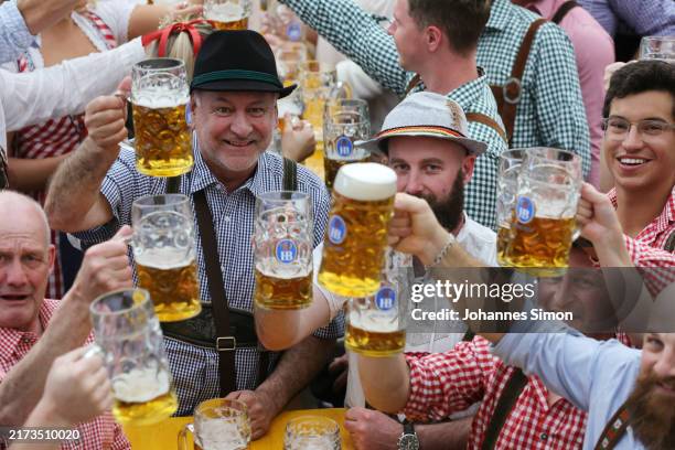 Revelers cheer with 1-liter-mug of beer at Paulaner beer tent during the opening day of the 2024 Munich Oktoberfest, Munich's annual beer festival,...