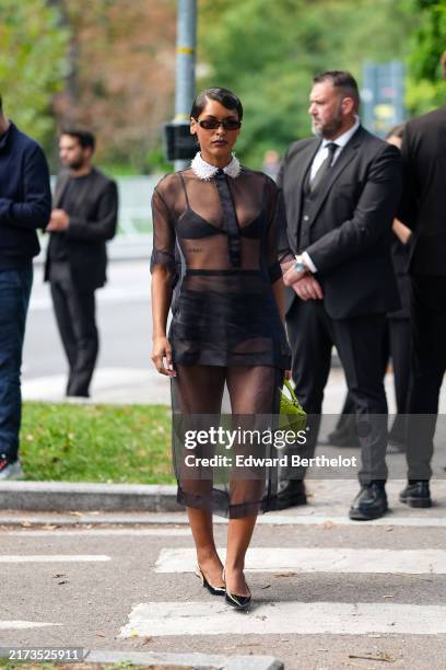 Guest wears black sunglasses, a black sheer top, a black sheer skirt, a green leather bag, black leather pointes shoes, outside Gucci, during the...