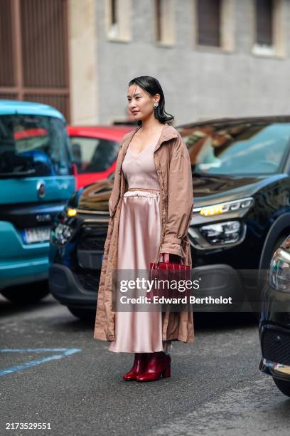 Guest wears silver earrings, light pink v-neck t-shirt, shiny light pink satin midi skirt, dark pink trench coat, shiny dark red leather bag, shiny...