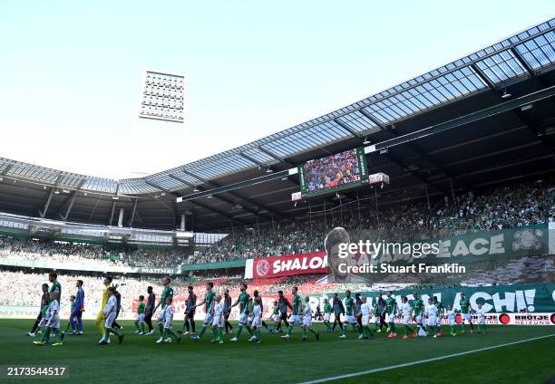 Players walk out as fans display a tiffo that reads "Shalom, salam, peace, may your memory be a revolution, achi" during the Bundesliga match between...