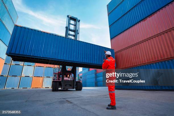 confident engineer and tablet at containers yard from cargo freight ship for import export. dock control worker wearing protective coveralls against stack of a containers terminal. logistic and transportation. global business concepts. - computer loading stock pictures, royalty-free photos & images