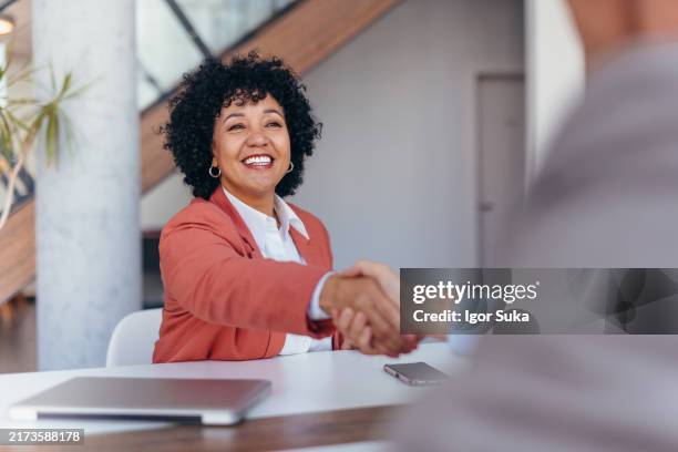 femme souriante au bureau saluant avec une poignée de main lors d’une réunion. - initiative photos et images de collection